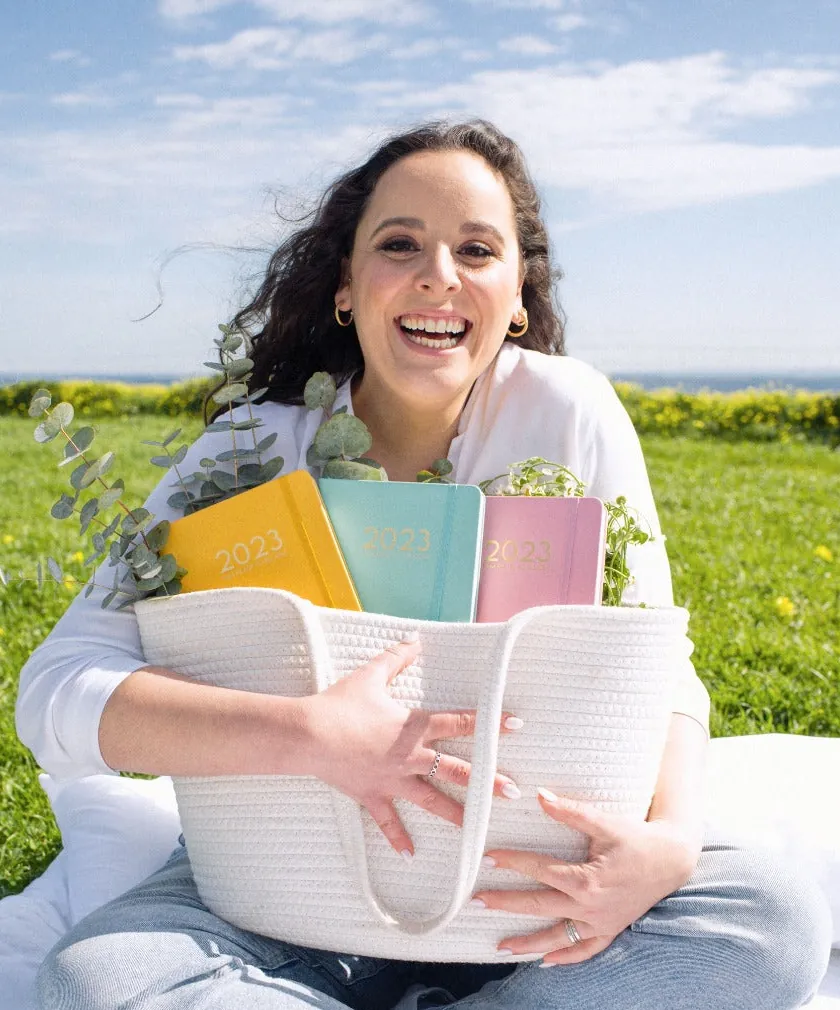 Marisa Maisterra, fundadora de I Am Ready To Bloom, sentada en el pasto con una canasta de planners.